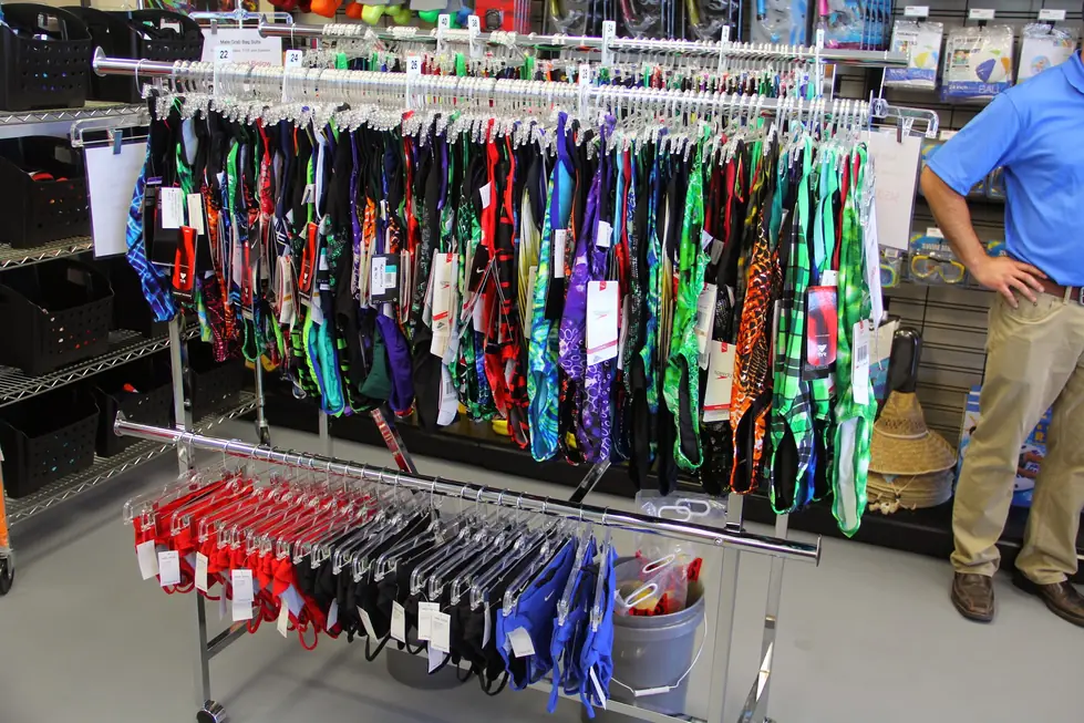 Racks of competitive team suits sorted by size at Champion Pool and Spa Supply